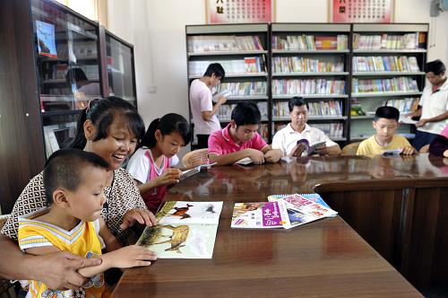 7月8日,广东梅县松源镇横坊村村民在“农家书屋”充电。连日来,随着梅州兴宁市福兴街道办事处、梅县松源镇、桃尧镇和隆文镇等20多个今年计划新增的“农家书屋”落成,由广东省新闻出版局统一资助建设,广东新华发行集团梅州新华书店有限公司负责承建的“农家书屋”工程建设工作在广东梅州市全面铺开。据悉,按计划到7月底可全面完成787个“农家书屋”建设任务。新华社发(钟小丰 摄)