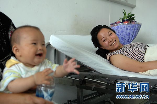 7月3日,当家人逗乐7个月大的儿子陈至轩时,躺在病床上的吴菊萍也露出笑容。 新华社记者 黄宗治 摄