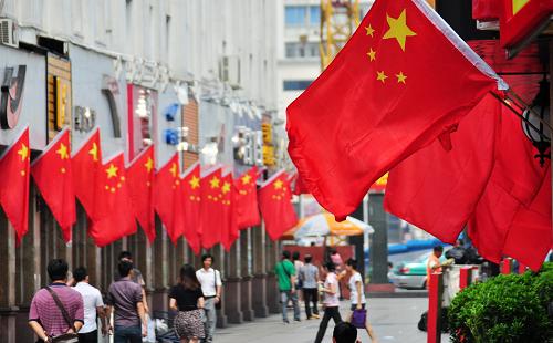 9月29日,在广西南宁市民生路,市民从国旗高挂的步行街上走过。国庆节临近,五彩缤纷的鲜花、红旗等把壮乡首府广西南宁装扮一新,营造祥和、喜庆的节日氛围。新华社发(陆波岸 摄)