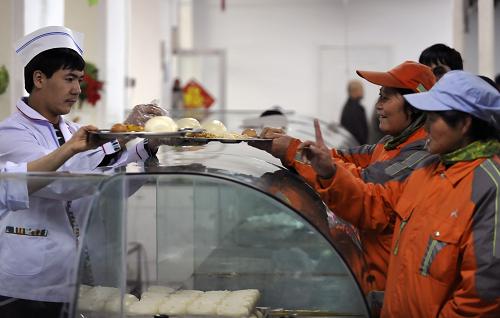 11月28日,几名环卫工人在乌鲁木齐市沙依巴克区八一街道办事处新疆职业病医院就餐点内领取早餐。 当日,乌鲁木齐市沙依巴克区八一街道办事处在新疆职业病医院就餐点内,为辖区内约400名环卫工人试供应免费早餐。沙依巴克区还将根据实际情况为夜班环卫工人提供免费夜宵。乌鲁木齐市委、市政府日前决定,从2011年12月1日起,为每位早班作业的环卫保洁员提供一份标准早餐,由各街道办事处就地、就近选定供应点,也可通过配送车辆发放,所需费用由市、区两级财政全额承担。 目前,乌鲁木齐现有公益性环卫保洁员1.9万名,其中,每天上早班的约有1.2万人,他们每天早晨6点就开始上岗工作。由于工作的时限性和特殊性,多数人早上只能啃点干馕,吃点凉饭,连热水都喝不上。随着严冬逼近乌鲁木齐,当地清除冰雪任务加重,这一问题更加突出。 新华社记者 赵戈 摄